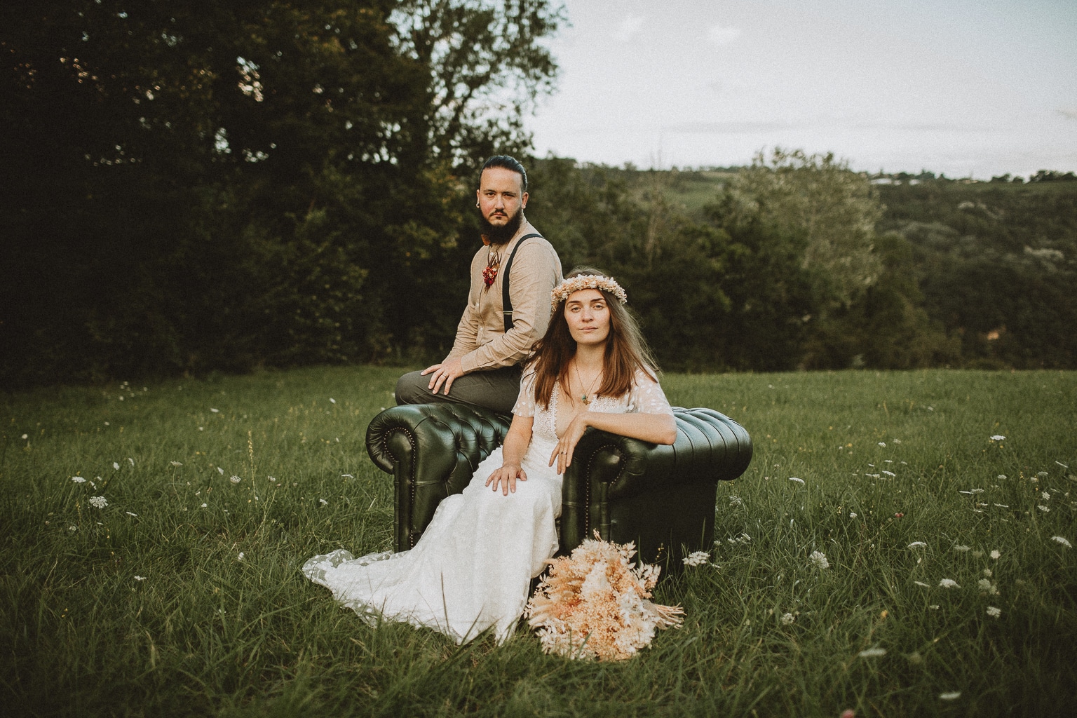 Couple de mariés assis dans un fauteuil au milieu d'un champs