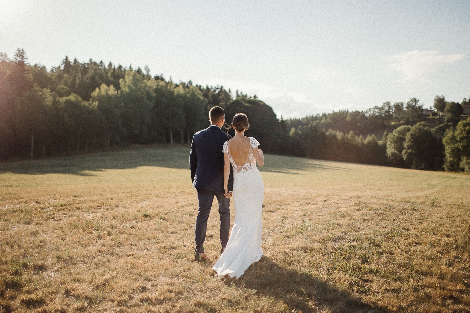 Couple de mariés de dos marchant dans le parc d'un domaine